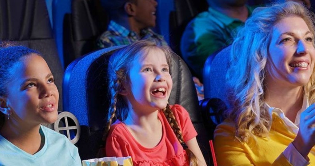 kids and woman sitting in movie theater smiling