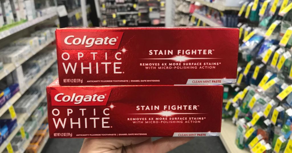 hand holding two boxes of Colgate optic white toothpaste