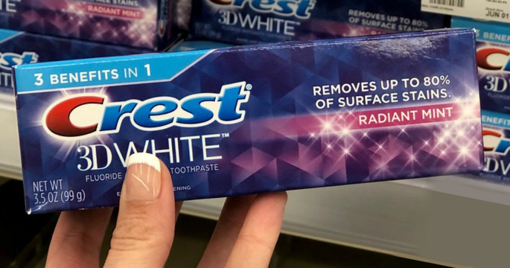Woman's hand holding Crest 3D White toothpaste in box at Walgreens