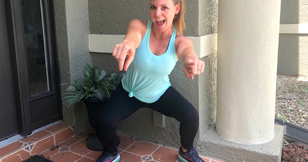 woman pointing at camera while doing squat 
