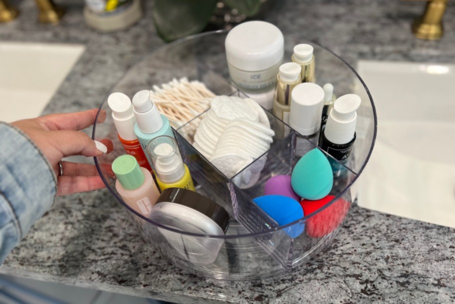A clear turntable organizer filled with makeup and beauty supplies