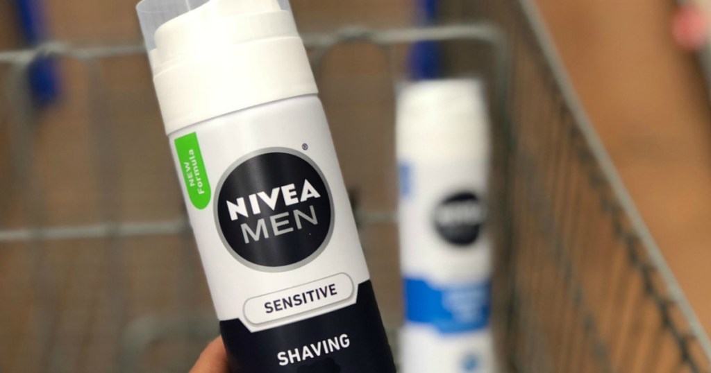 hand holding a white bottle of Nivea Shaving gel in front of shopping cart.