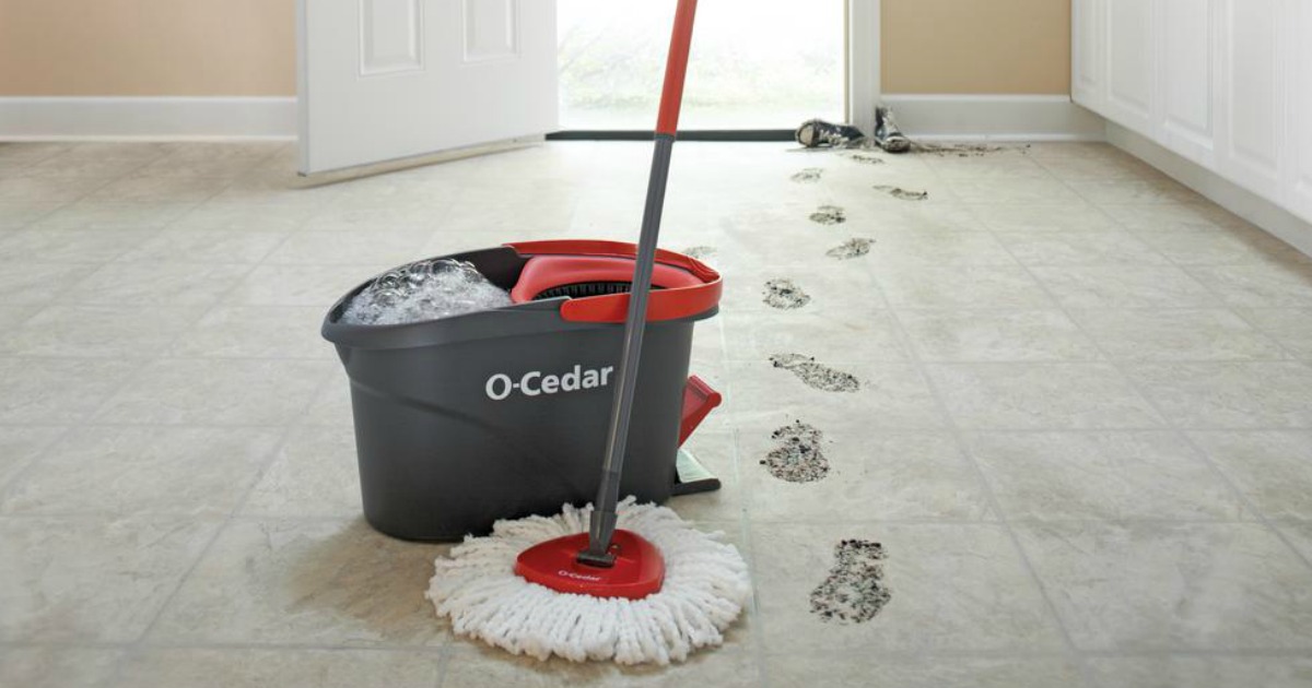 O-Cedar spin mop and bucket on floor next to dirty footprints in front of an open door