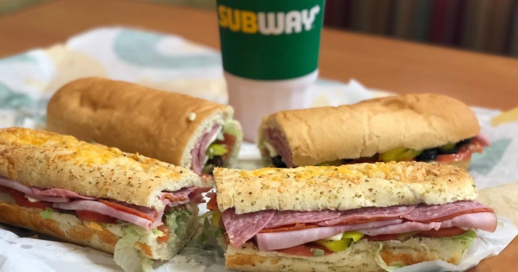 two subway subs and a drink on a table