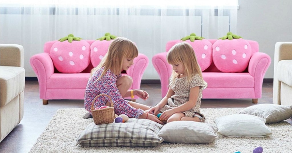 two girls sitting in front of pink couches with strawberry pillows