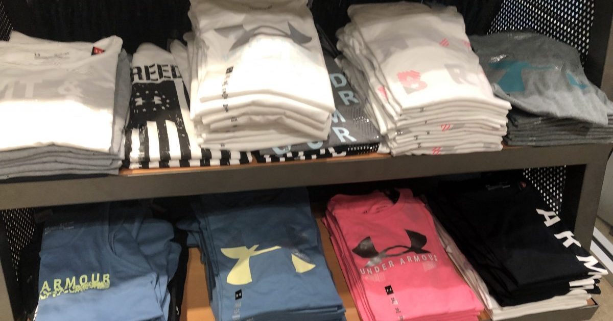 Under Armour Tees in various colors folded on a store display shelf