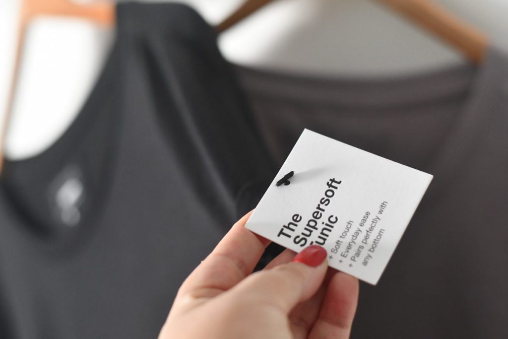 hand holding the supersoft tunic tag with blurry background