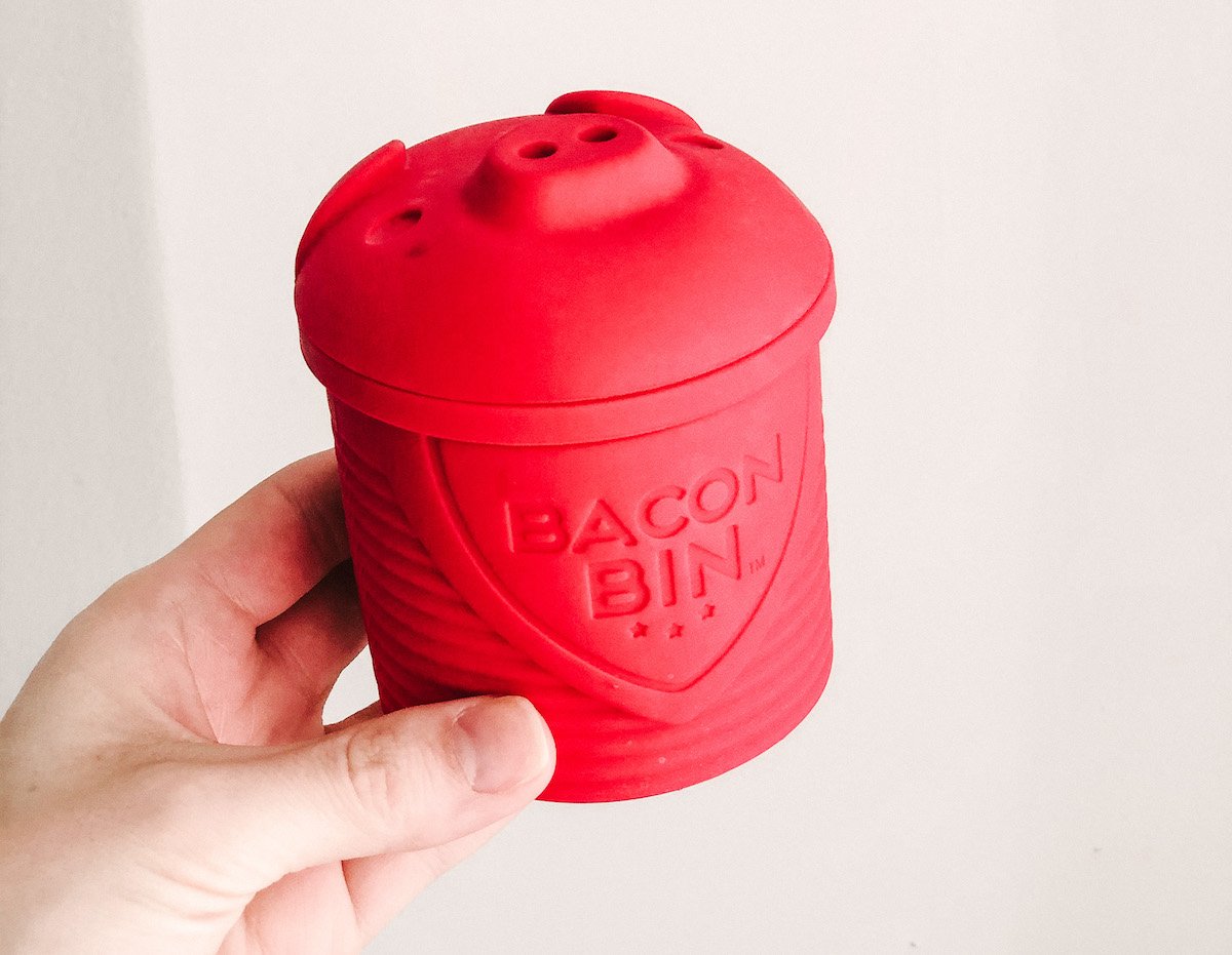 hand holding a red pig shaped bacon bin