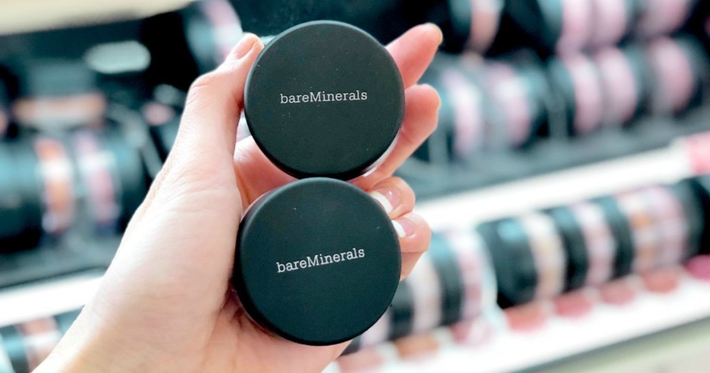 Woman holding bareMinerals products with blurred background
