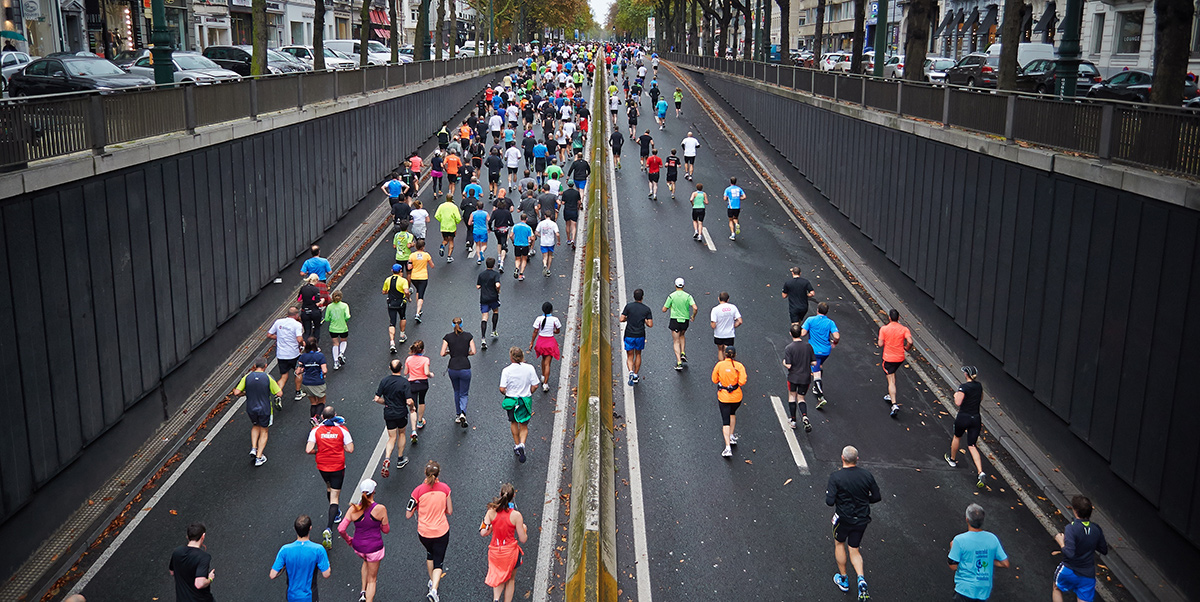 large group of people running on highway in organized race workout accountability app