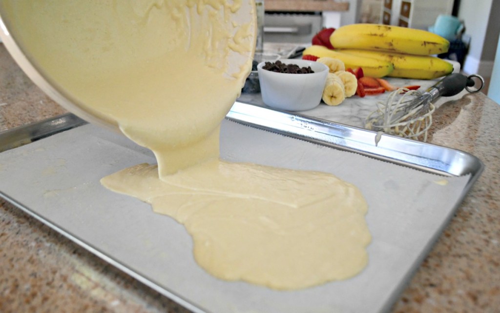 pouring pancake batter onto a sheet pan