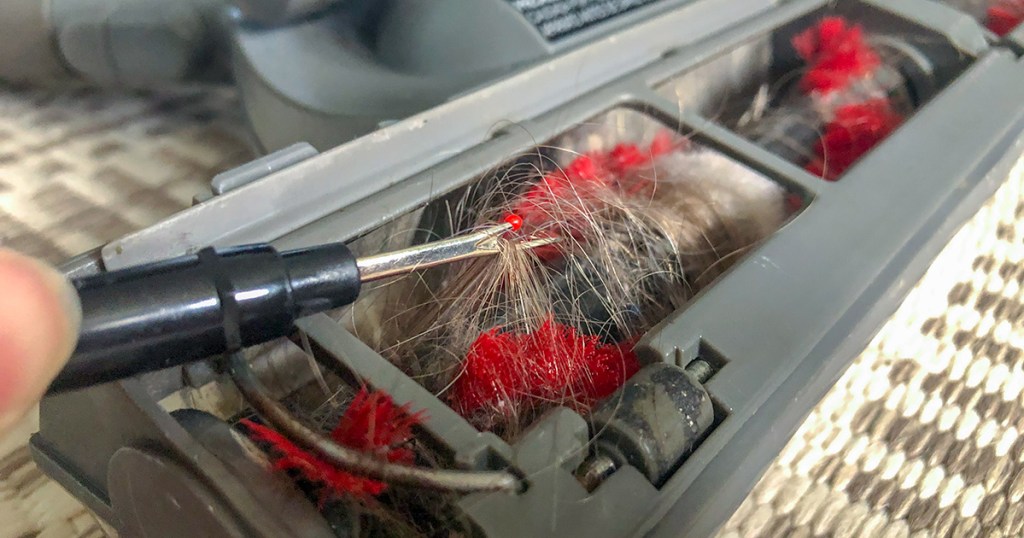 seam ripper cutting out tangled hair from vacuum brush