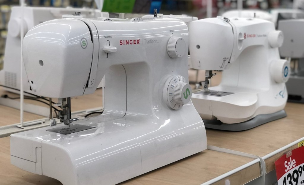 two white singer sewing machines sitting on store shelf