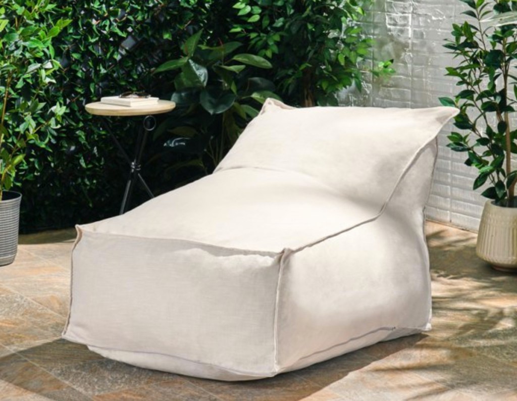 cream colored outdoor bean bag lounger sitting on restoration hardware patio furniture outside
