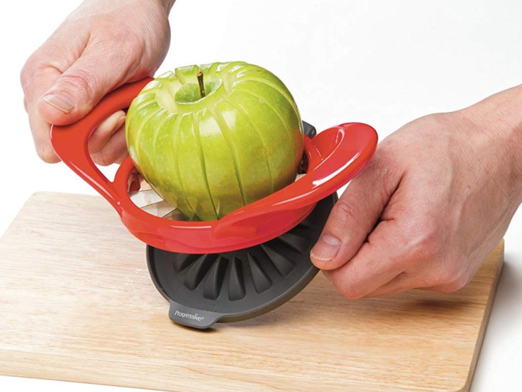 hand slicing green granny smith apple on wooden cutting board