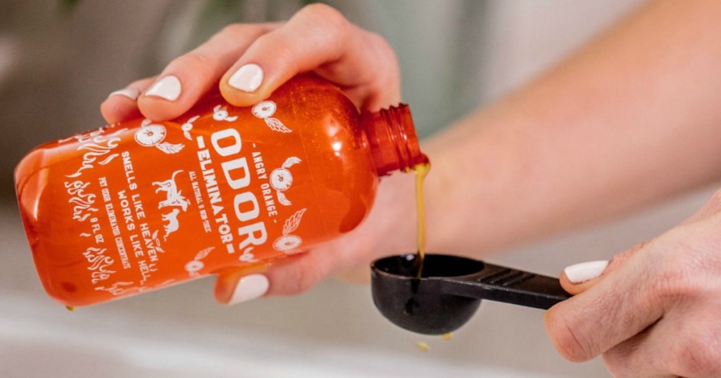 woman pouring angry orange odor eliminator into measuring spoon