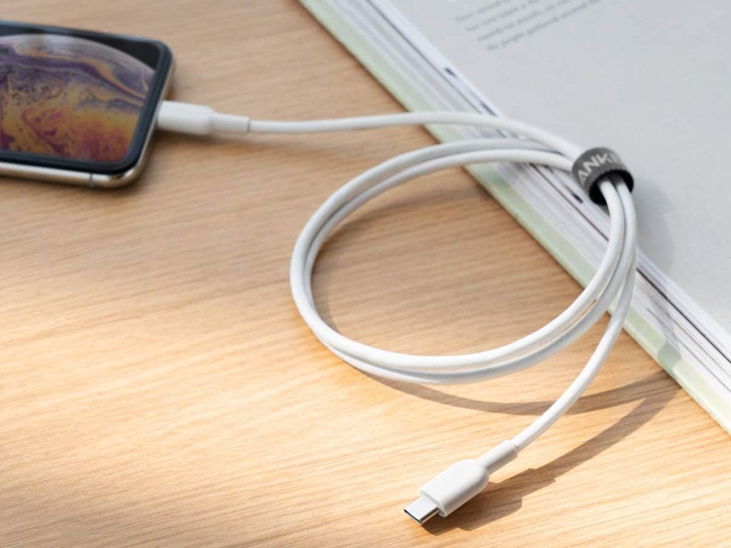 anker usb c to lightning cable wire plugged into iphone x on table with book