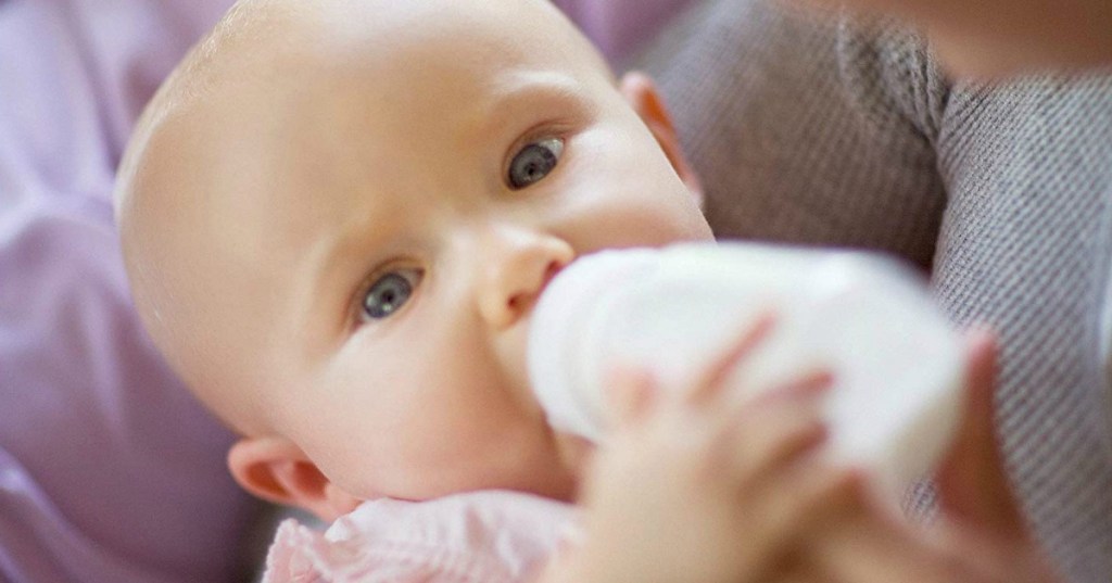 baby being held while eating from a bottle