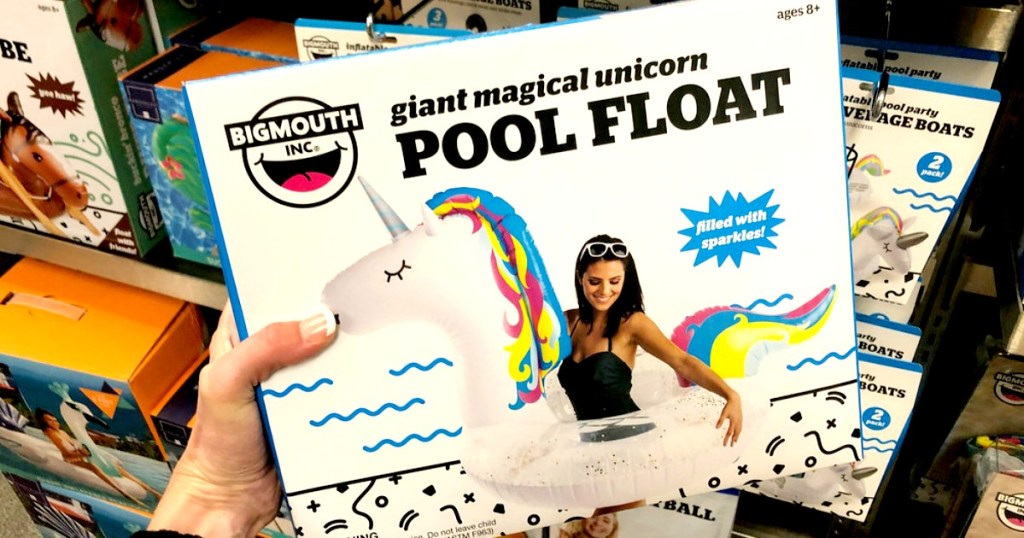 Big Mouth Unicorn Pool Float being held by woman's hand in front of other pool floats