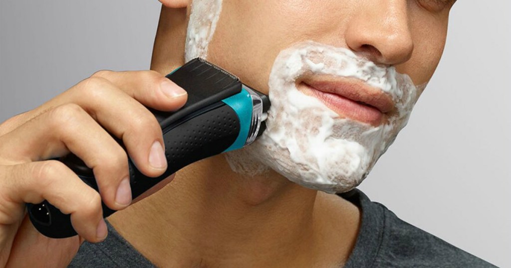 Man covered in shaving cream using Braun shaver to shave cheek