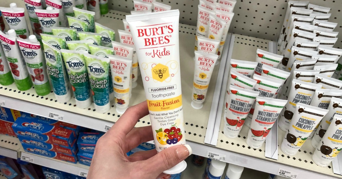 hand holding Burt's Bees Kids Toothpaste in front of a store shelf
