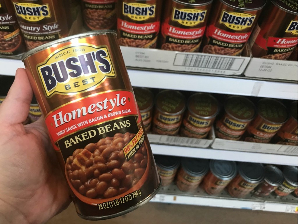 Large can of bush's baked beans being held up at grocery store