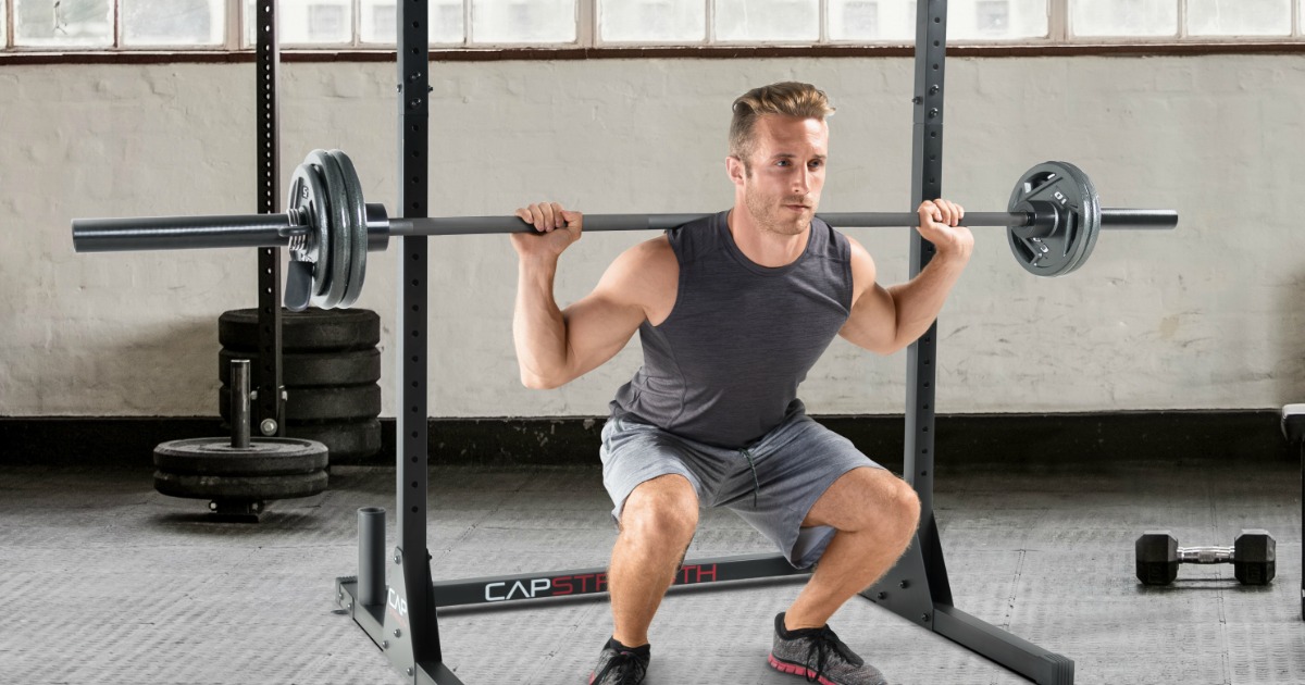 man doing squats while lifting barbell over shoulders in gym