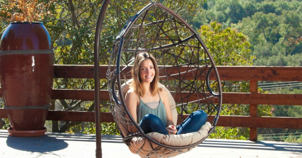 Woman sitting in Christopher Knight Home Outdoor Wicker Tear Drop Hanging Chair on a deck