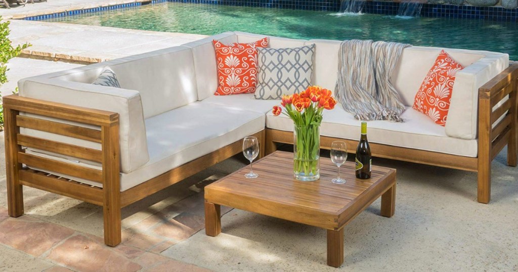 Christopher Knight Home Ravello 4-Piece Outdoor Acacia Wood Sectional Set by pool with flowers, wine and wine glasses on table