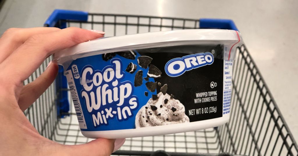 Hand holding Cool Whip Mix-ins Oreo in walmart with cart in background