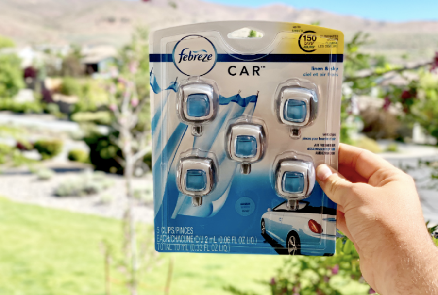 Hand holding Costco Febreze Air Vent Clips with outdoor blurred background