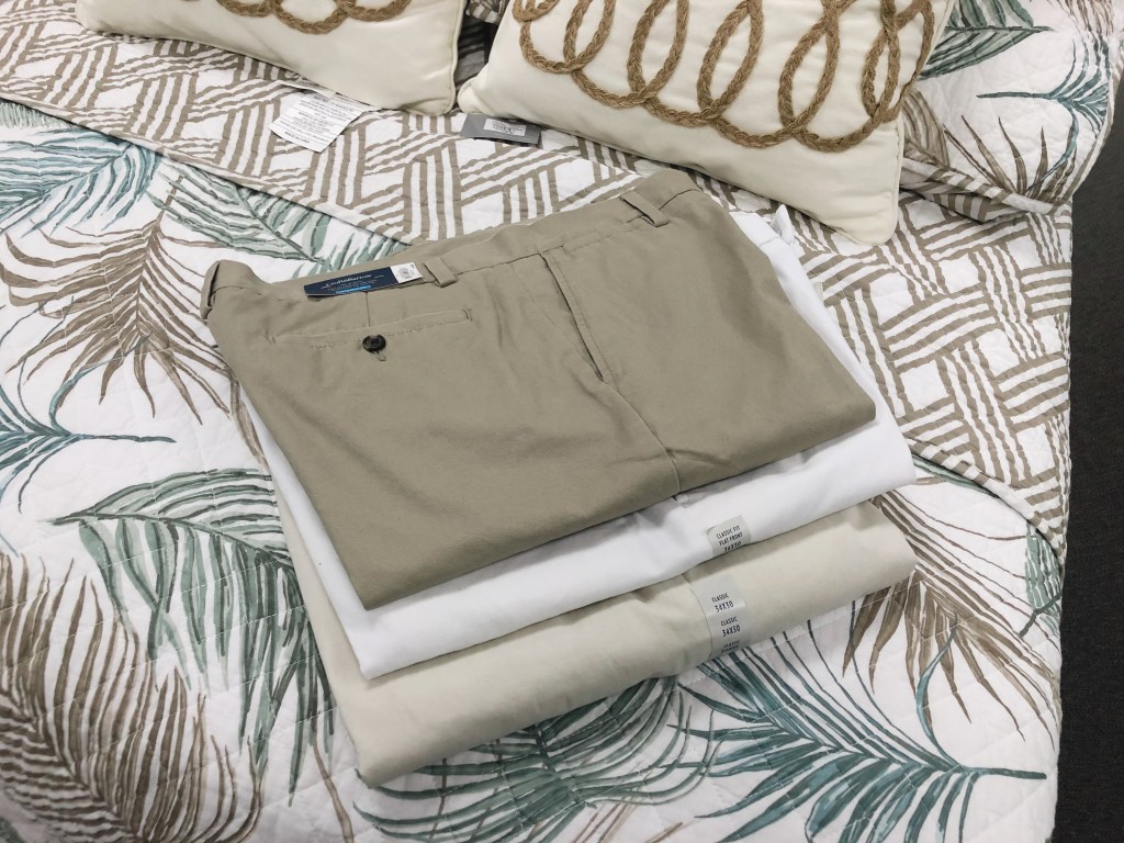 three pairs of men's pants sitting on a bed