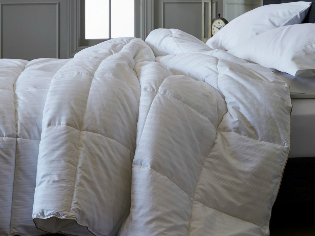 white duvet bunched up on bed with white pillows 