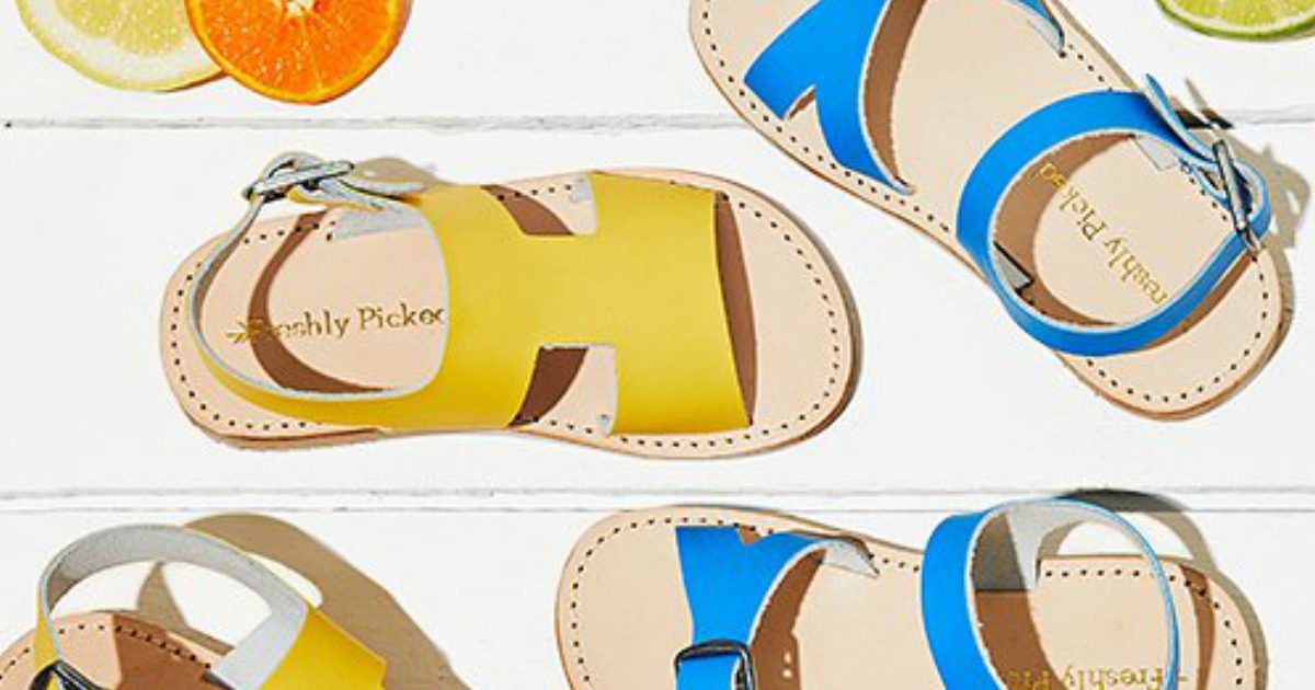 blue and yellow Freshly Picked Leather Sandals for Baby on white wooden background