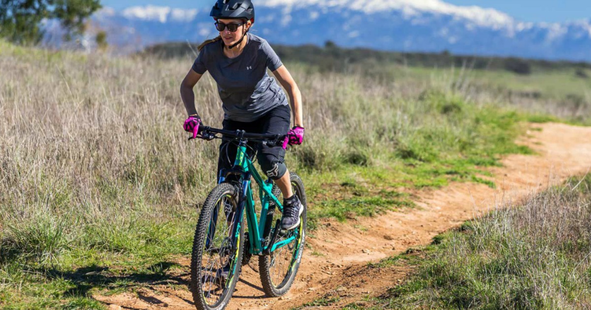 woman wearing helmet riding a mountain bike on a dirt trail