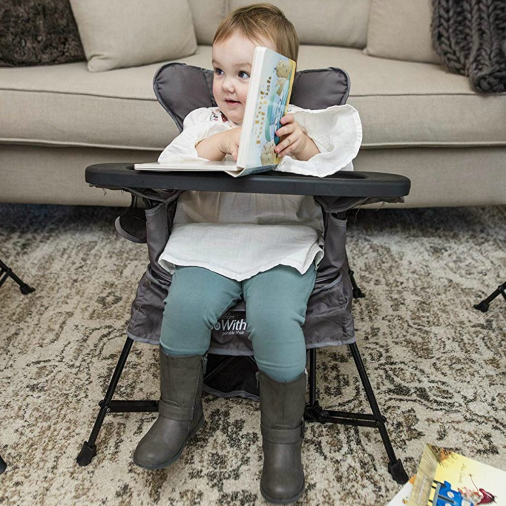 Baby reading a book in a grey portable chair