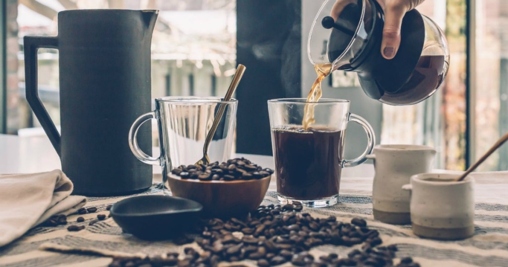 Coffee beans on counter next to french press coffee maker