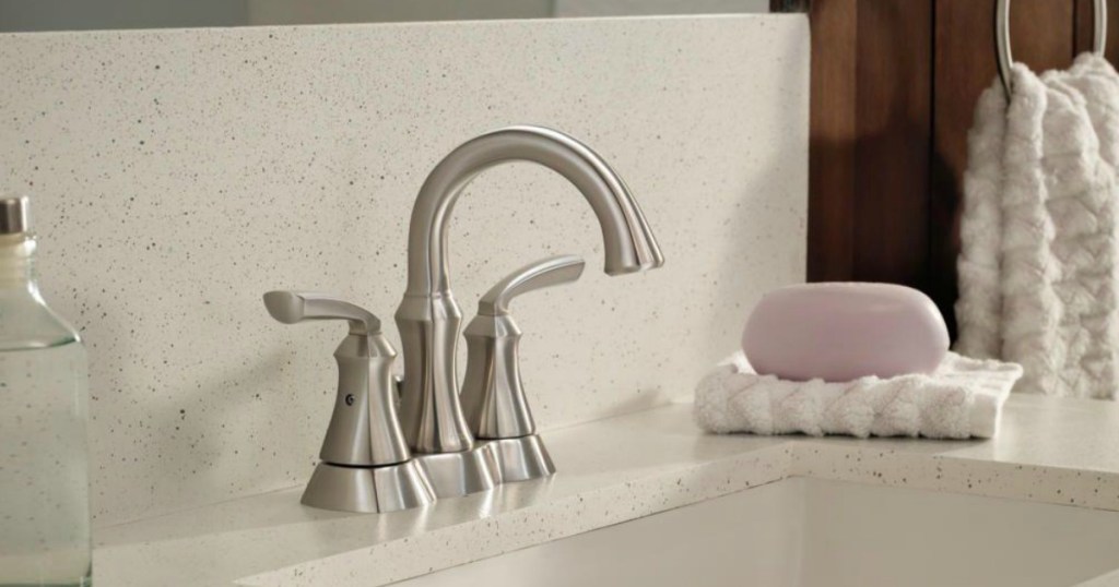 nickel faucet in bathroom sink with pink soap and white towels
