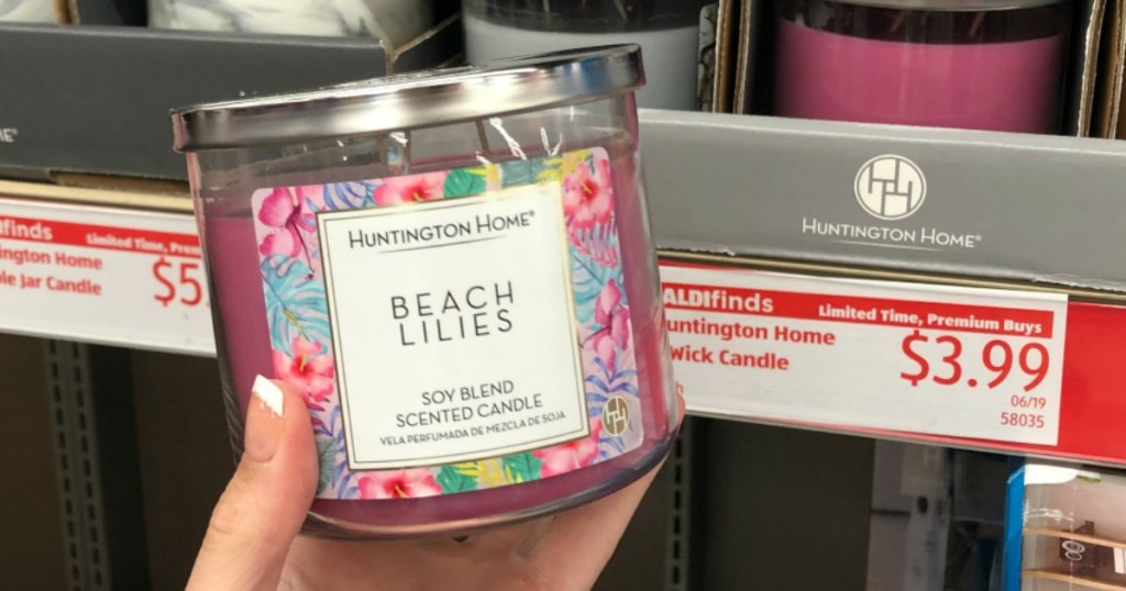 Woman holding Huntington Home 3-Wick candle in Beach Lilies inside ALDI store