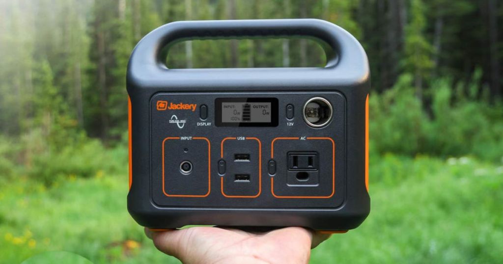 Hand holding Jackery Portable Power Station in forest