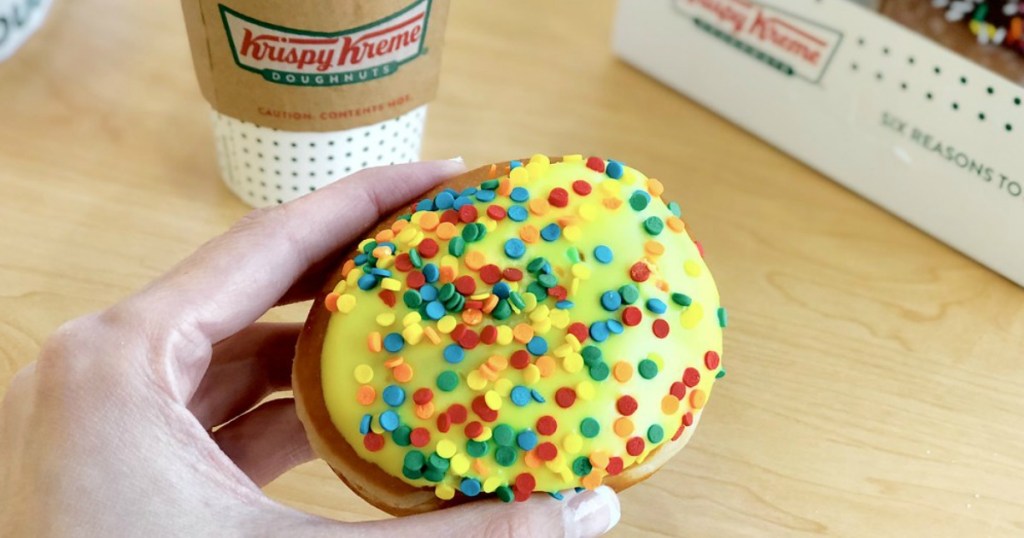 Krispy Kreme Doughnut being held by a woman with a coffee