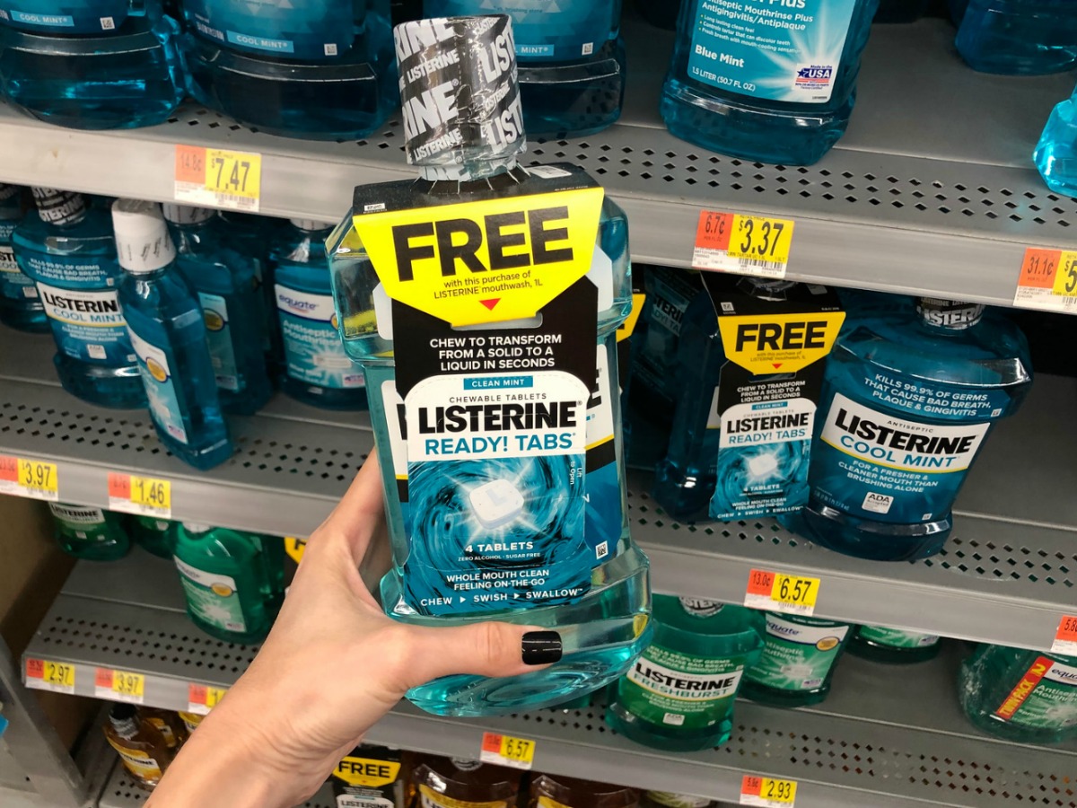 Hand holding Listerine bottle in front of store shelves