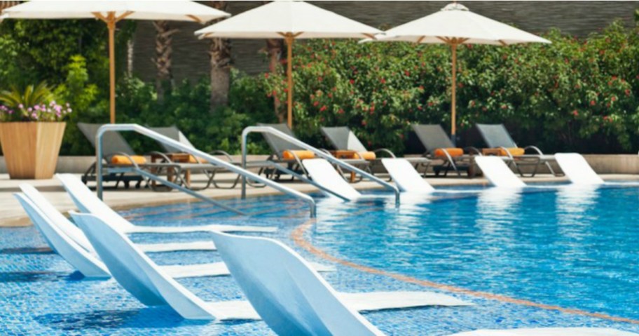 pool surrounded by pool seats and umbrellas which may be accessed thanks to a teacher discount