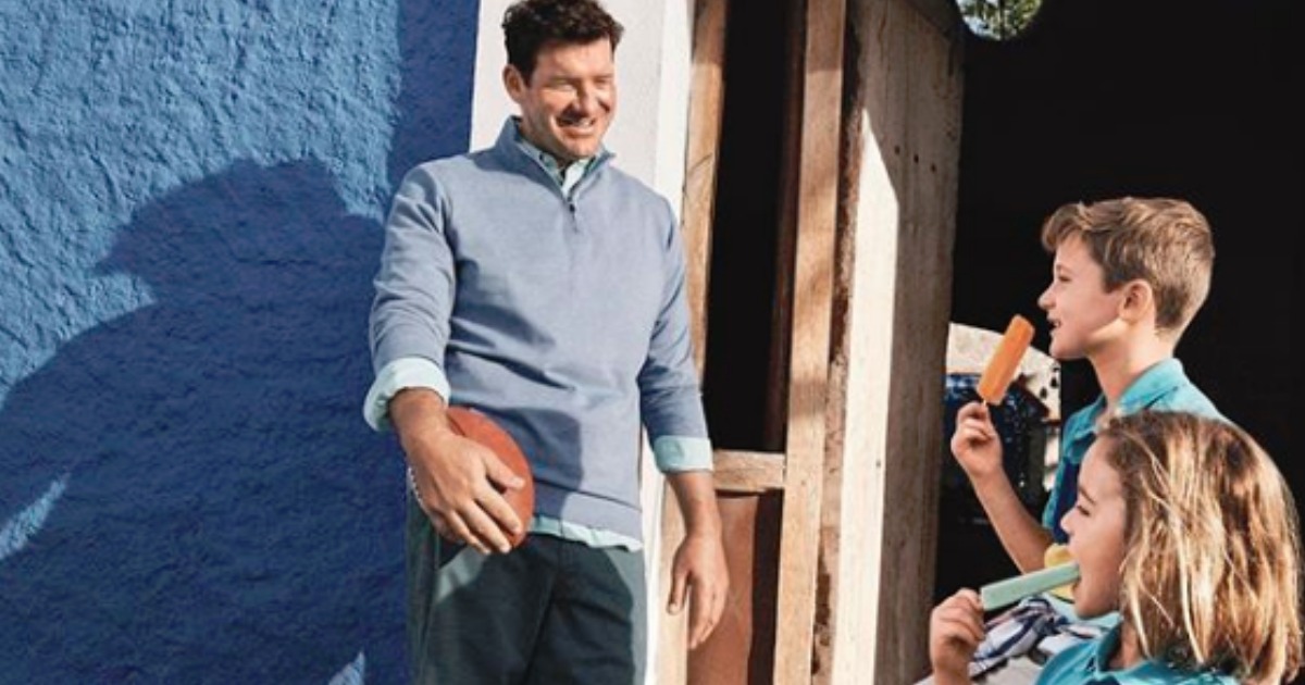 Tony Romo holding football wearing blue pullover talking to kids eating popsicles