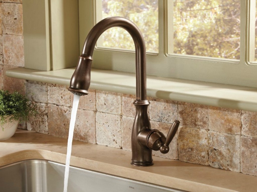 bronze faucet with water running in kitchen sink