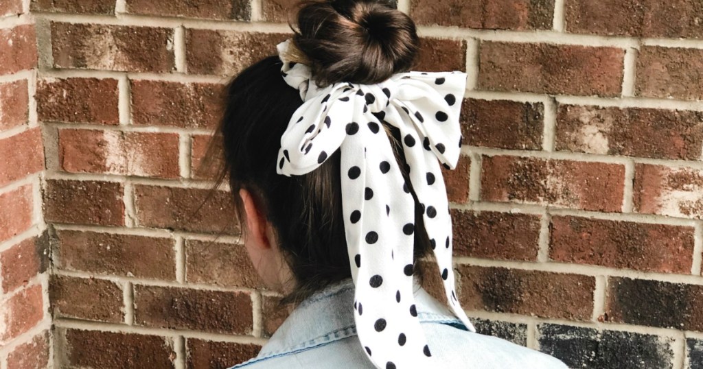teen girl with white and black dot hair bow standing in front of brick wall