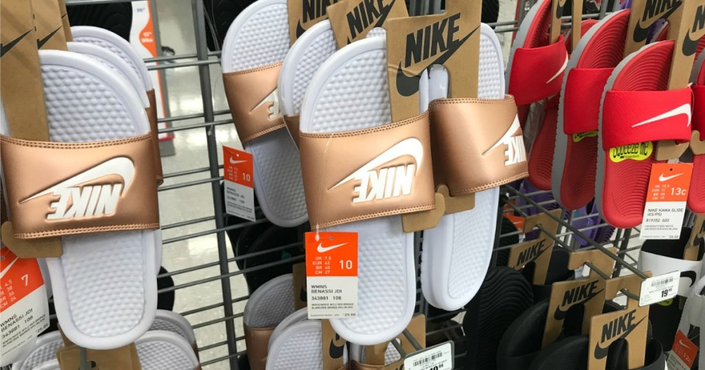 Nike benassi slides in white and gold hanging on a rack at Academy
