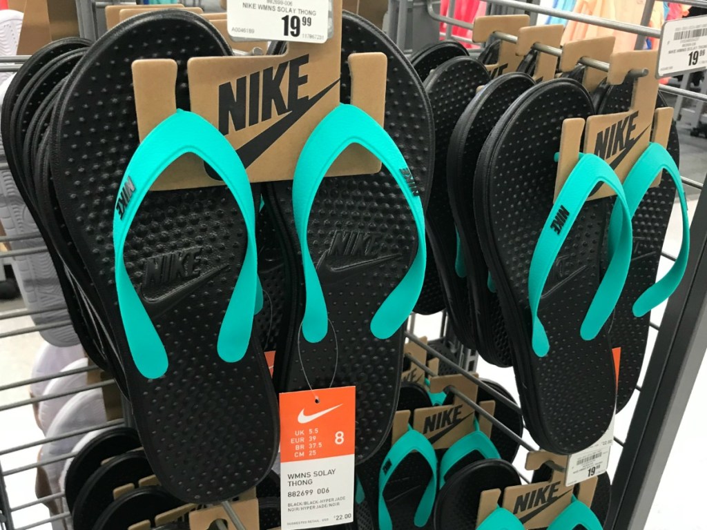 Teal and black Nike flip-flops hanging on rack at Academy