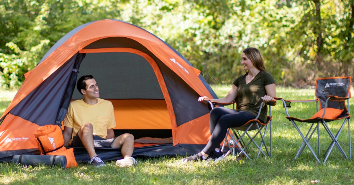 man sitting in tent by woman sitting in camping chair