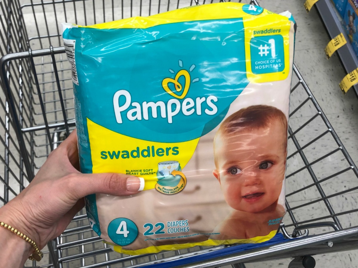 woman holding Pampers Swaddlers diapers over Walgreens shopping cart
